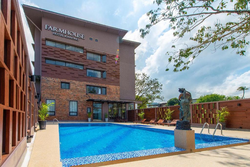 a hotel with a swimming pool in front of a building at The Farm House Hotel Ranong in Ranong