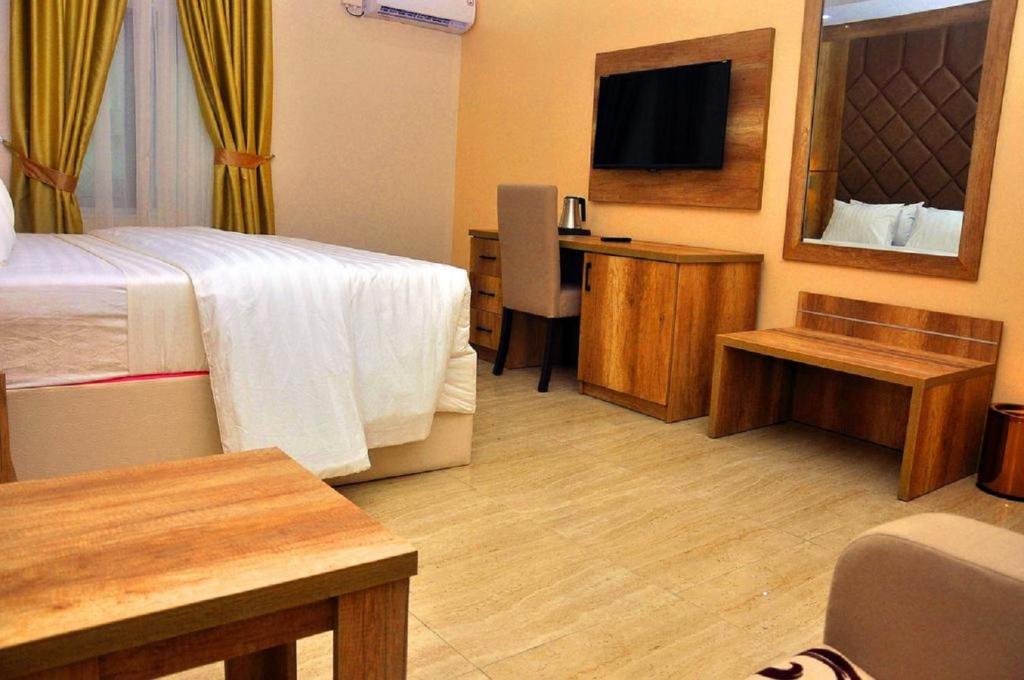 a hotel room with a bed and a desk and a television at Lit Suites in Abuja