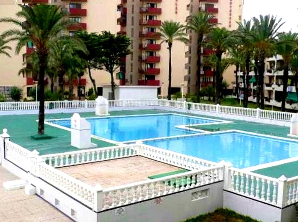 a large swimming pool with palm trees and buildings at 2 bedrooms appartement at San Javier 100 m away from the beach with sea view shared pool and furnished balcony in La Manga del Mar Menor