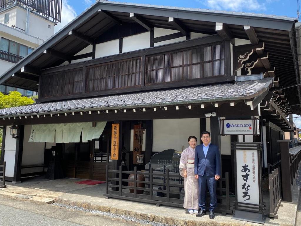 a man and a woman standing in front of a building at Ryokan Asunaro in Takayama