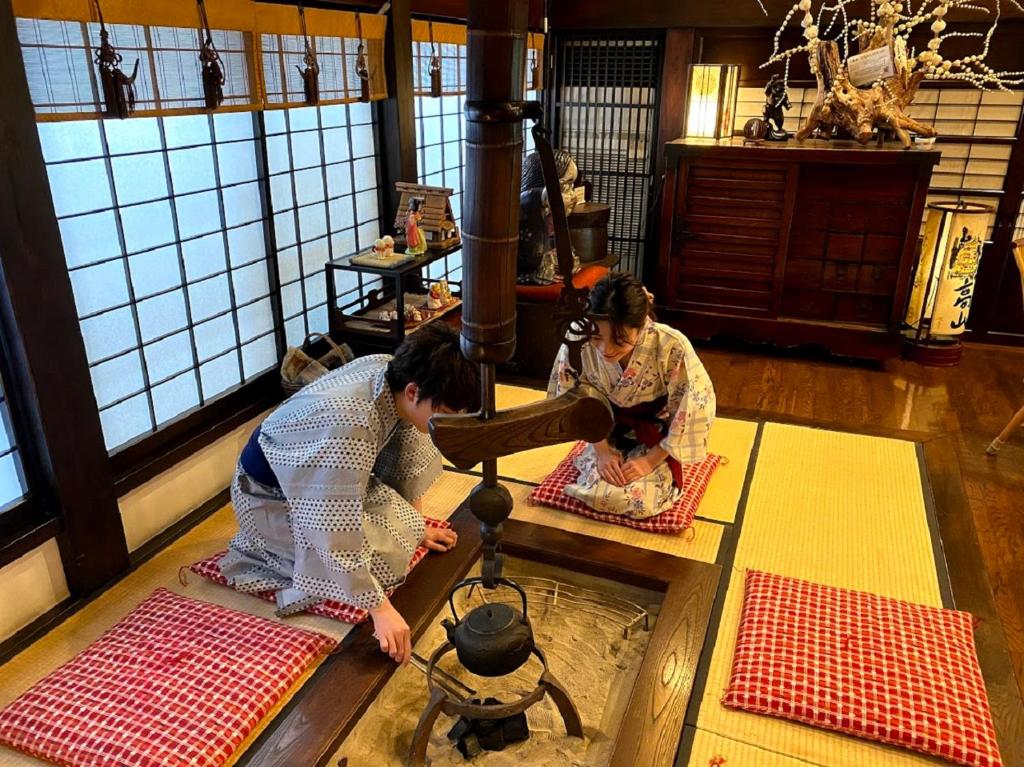 two women are sitting in a room with a table at Ryokan Asunaro in Takayama