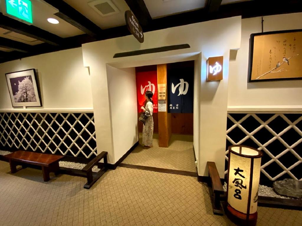 a lobby with a woman standing at the door at Ryokan Asunaro in Takayama