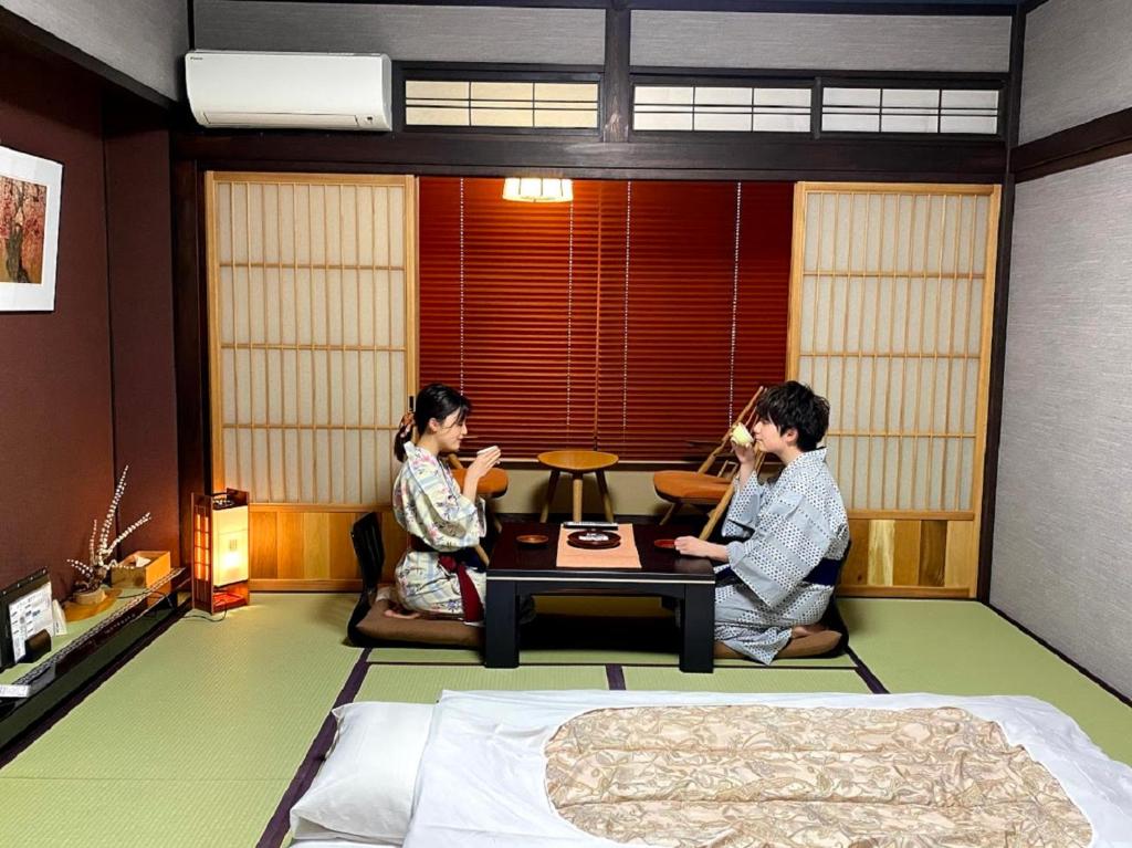 two people sitting at a table in a bedroom at Ryokan Asunaro in Takayama