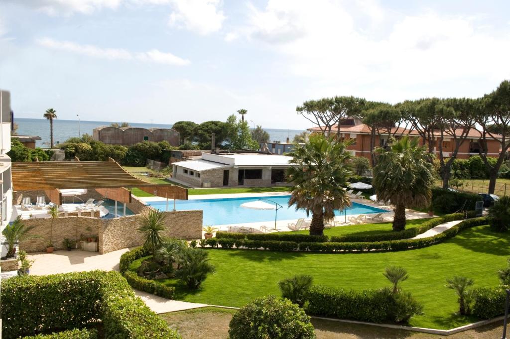 a large green lawn with a pool in the middle of it at Albergo Mediterraneo in Terracina