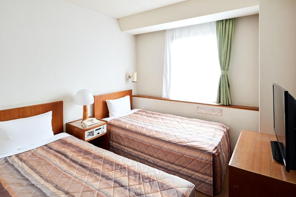 
a bedroom with two beds and a television at Marroad Inn Tokyo in Fuchu
