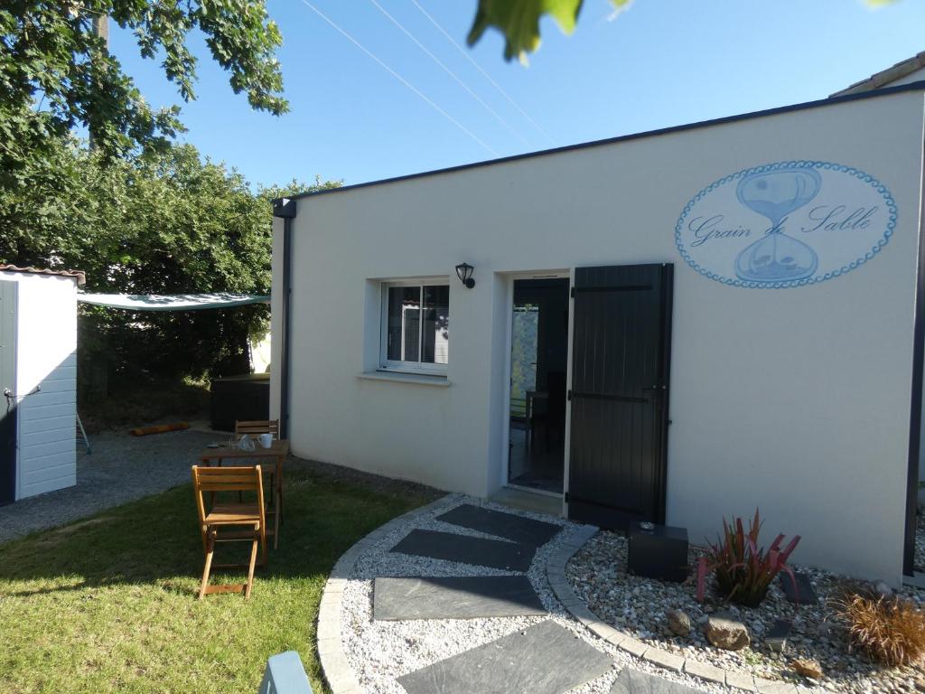 una casa blanca con una puerta negra y un patio en Grain de Sable et son Jacuzzi, en Talmont