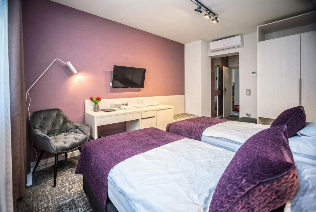 ザラエゲルセグにあるPiccolo Panzió Vendéglő Vinotecaのベッド2台とデスクが備わるホテルルームです。