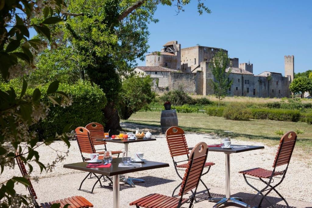 un grupo de mesas y sillas con un castillo en el fondo en Logis L'Auberge de Larressingle, en Larressingle