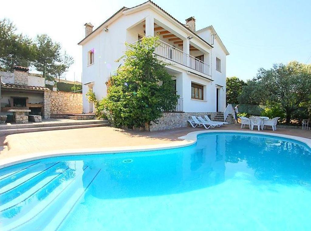 a large blue swimming pool in front of a house at Spacious Apartment in Canyelles with Private Pool in Canyelles