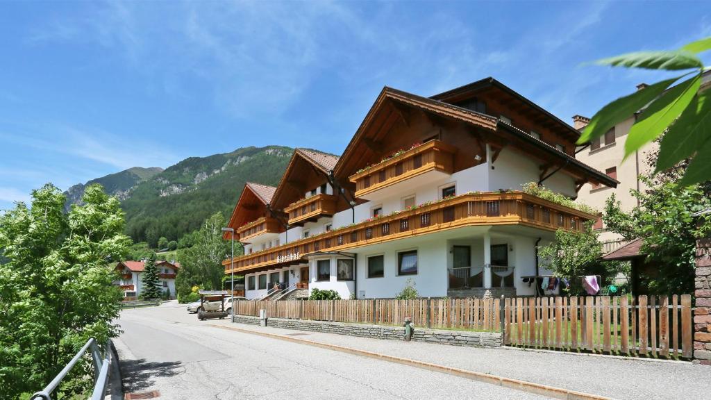 a building with a wooden fence on a street at Pension Alpenhof B&B in Colle Isarco