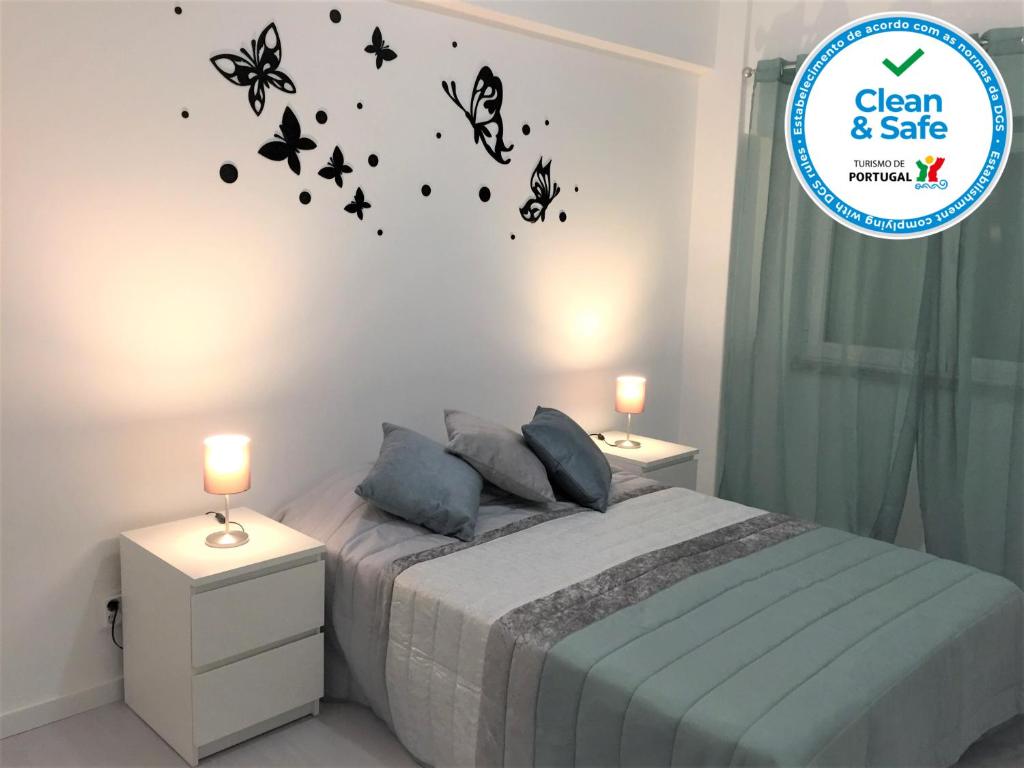 1 dormitorio con 1 cama con mariposas en la pared en Caparica Sol, en Costa da Caparica