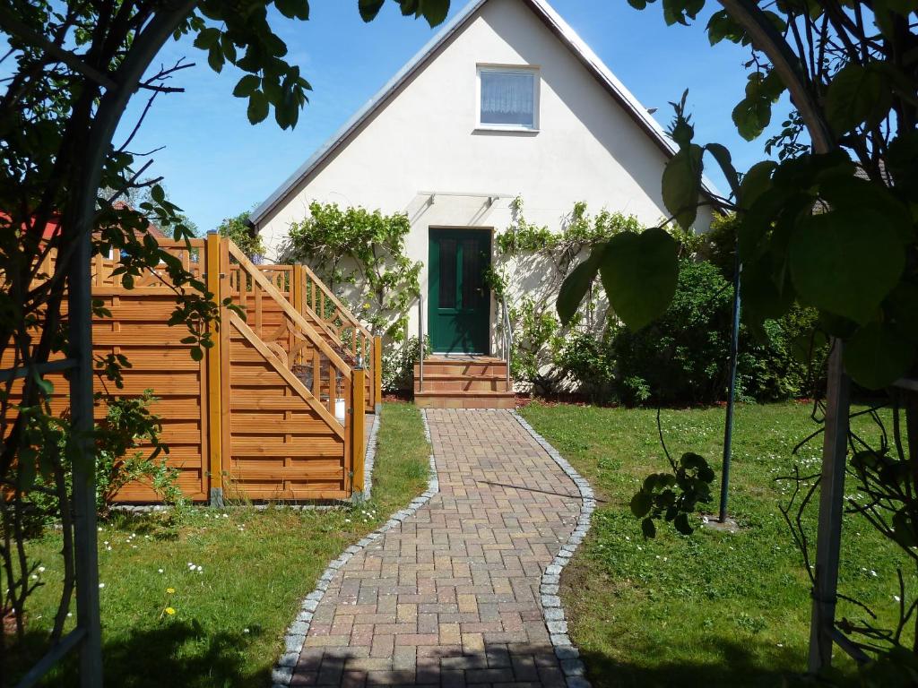 einen Weg zu einem weißen Haus mit grüner Tür in der Unterkunft Ferien auf Rügen Familie Geist in Garz