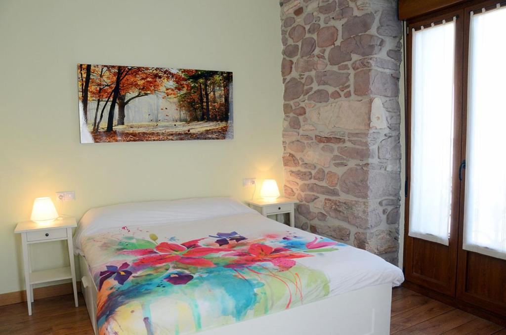 Un dormitorio con una cama con un cuadro en la pared. en Apartamentos Elizondo, en Elizondo