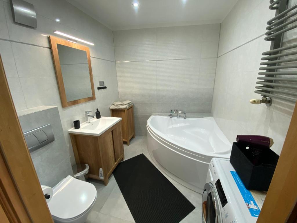 a bathroom with a tub and a toilet and a sink at Apartament Dwupoziomowy - klimatyzacja in Słupsk