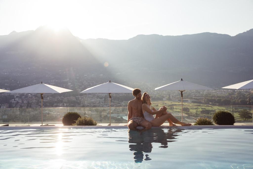 un hombre y una mujer sentados en el borde de una piscina en Giardino Marling, en Marlengo