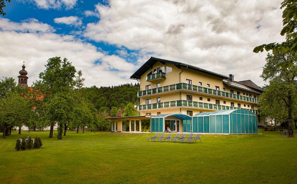 a large building in a park with a grass field at Landhotel Agathawirt in Bad Goisern