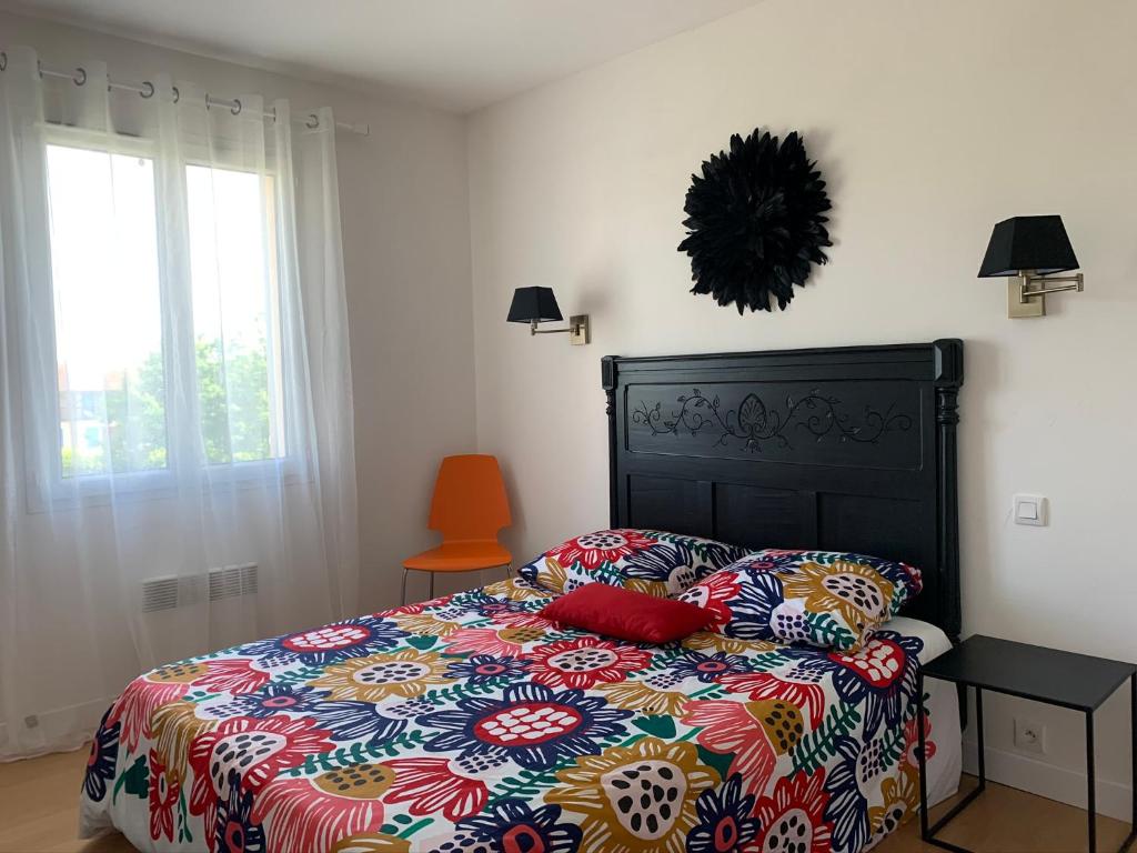 a bedroom with a bed with a colorful comforter and a window at Maison de vacances près de Marciac in Troncens