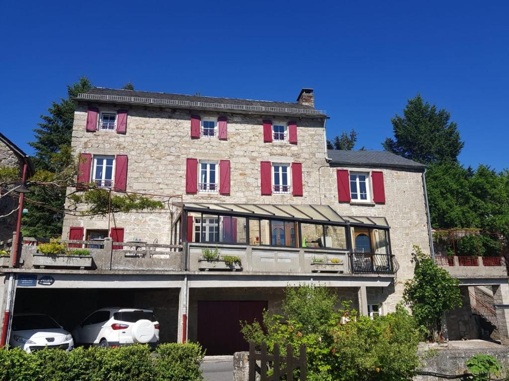 een groot bakstenen gebouw met auto's geparkeerd voor het bij Maison d'Hôtes "La Pierre Pointue" in Saint-Léons