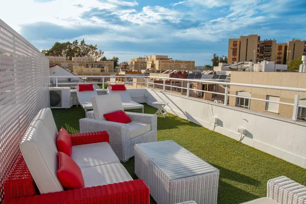 balkon z białymi i czerwonymi meblami na dachu w obiekcie Penthouse Raggio w Sewilli