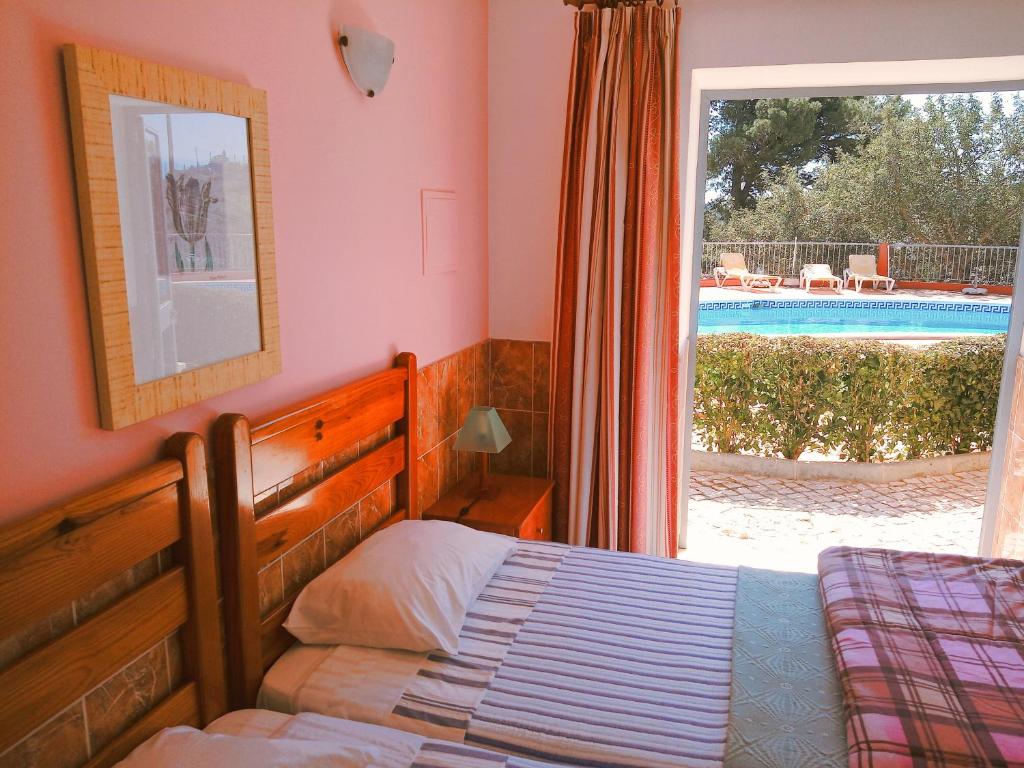Un dormitorio con una cama y una ventana con piscina. en Quinta dos Caracois, en Lagos
