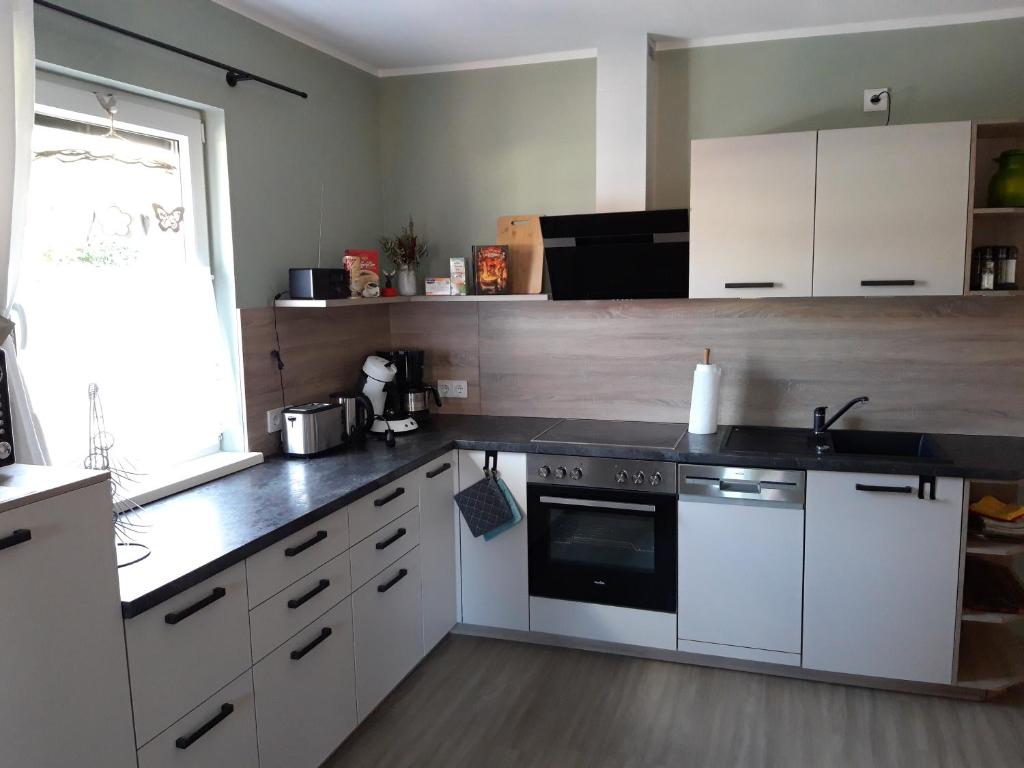 a kitchen with white cabinets and a black counter top at Ferienhaus am Riesenberg in Ellrich
