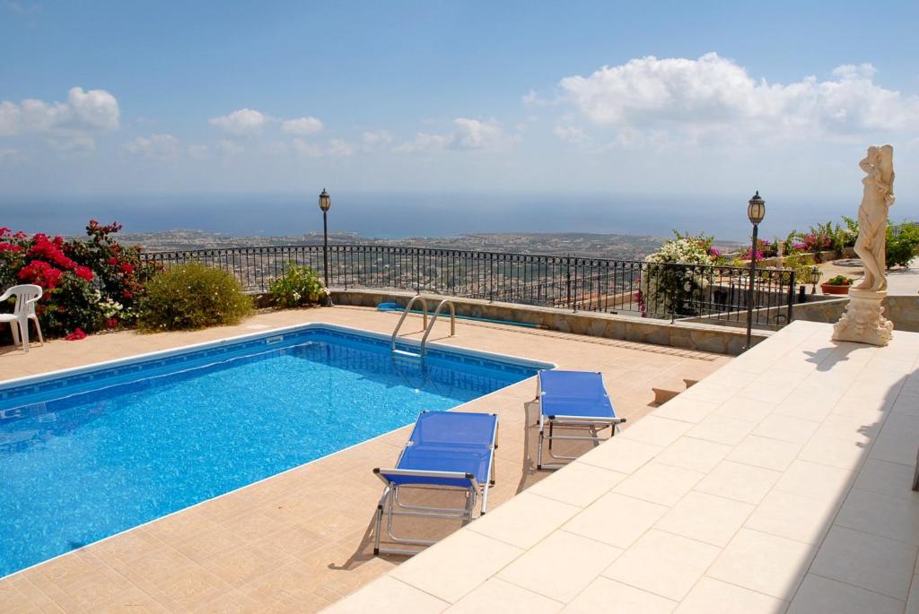 una piscina con 2 sillas azules y el océano en Peyia Villa with sea view, private pool, and garden, en Peyia