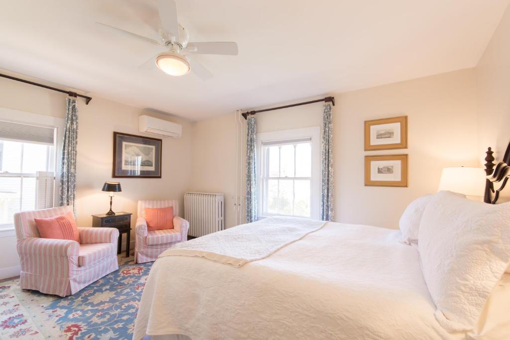 a bedroom with a white bed and two chairs at Marshall Slocum Inn in Newport