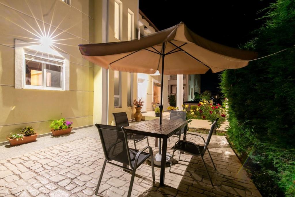 stół i krzesła z parasolem na patio w obiekcie Rose Garden House w mieście Kremasti