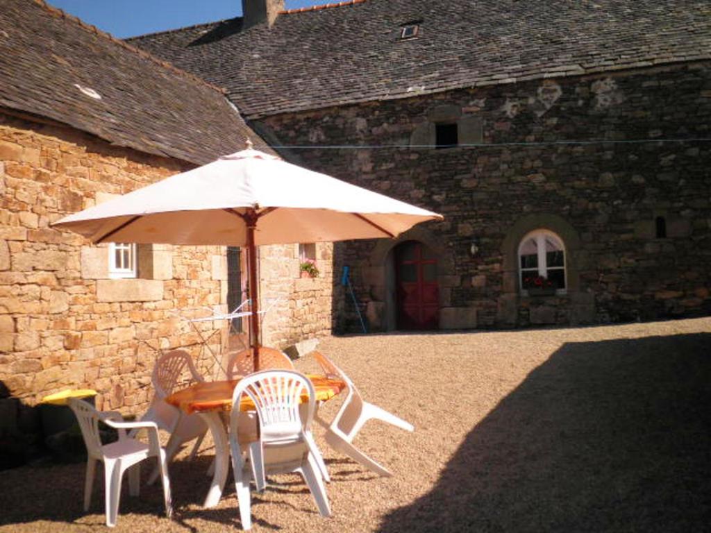 a table and chairs with an umbrella in front of a building at Maison de 3 chambres avec jardin amenage a Sibiril a 3 km de la plage in Sibiril