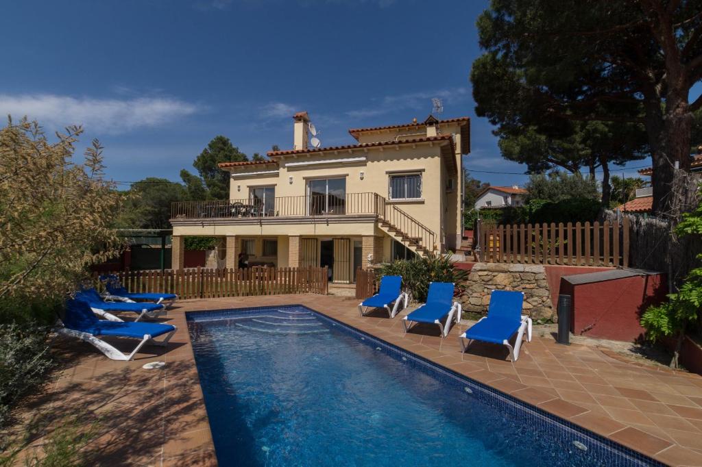 une maison avec une piscine entourée de chaises longues bleues dans l'établissement La Llevantina Boutique Villa, à Calonge