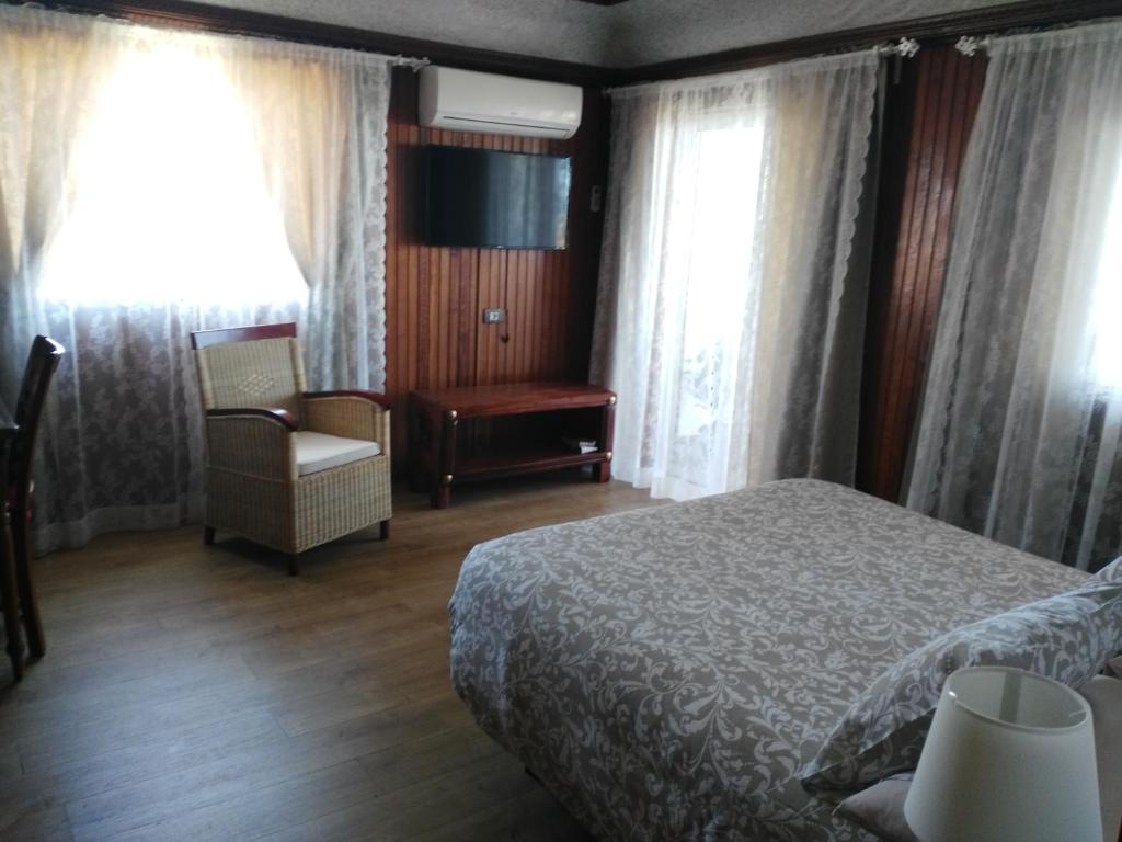 a bedroom with a bed and a chair and windows at HOSPEDAJE TU SITIO in La Esperanza