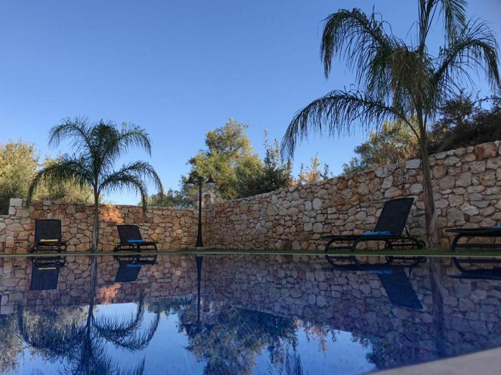 einen Pool mit zwei Stühlen neben einer Steinmauer in der Unterkunft Aktis luxury villa in Chania