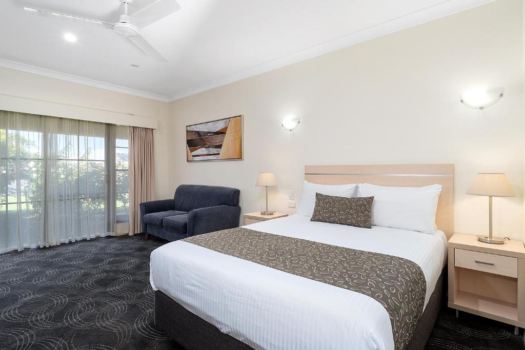 a hotel room with a bed and a chair at Heritage Motor Inn Corowa in Corowa