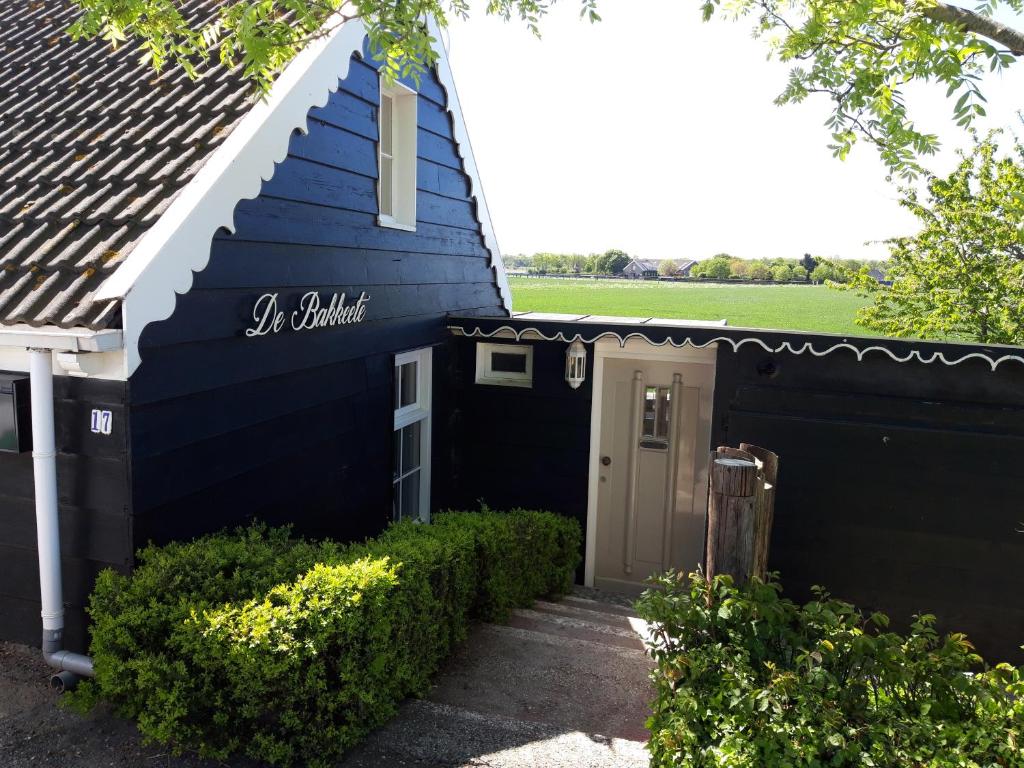 een blauw gebouw met een deur in een tuin bij strandhuis De Bakkeete A in Kamperland