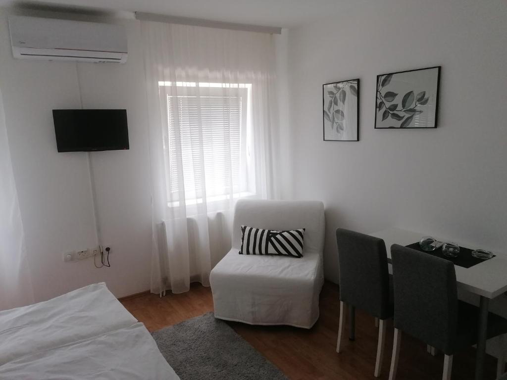 Dieses weiße Zimmer verfügt über einen Stuhl, einen Tisch und einen TV. in der Unterkunft Veliki Park in Šabac