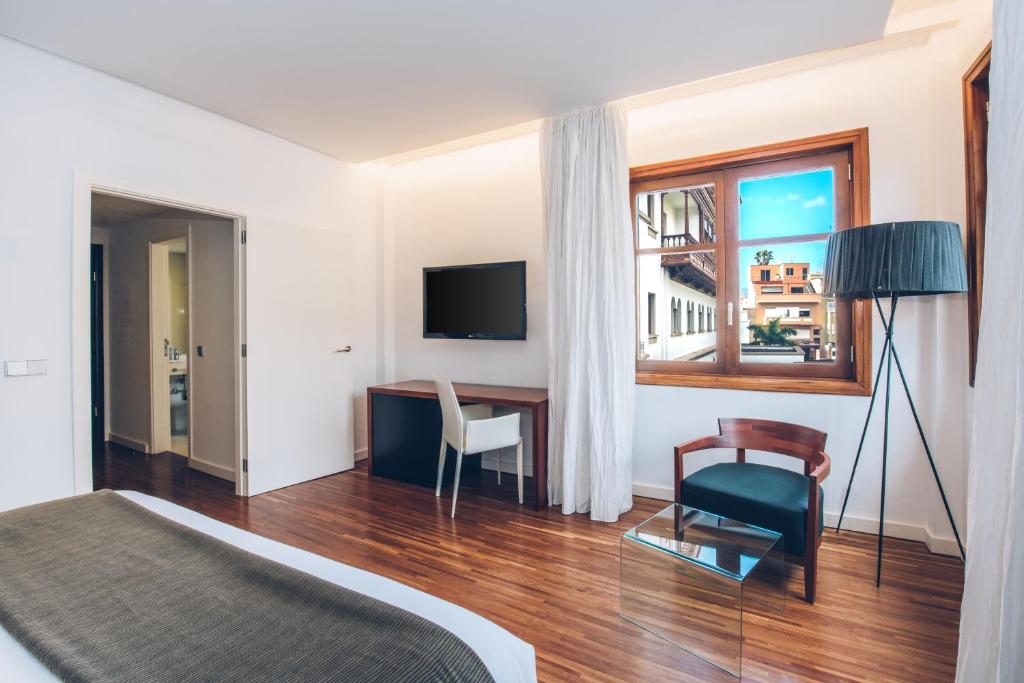a bedroom with a bed and a desk and a window at Iberostar Heritage Grand Mencey in Santa Cruz de Tenerife