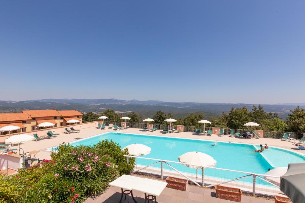 ein großer Pool mit Stühlen und Sonnenschirmen in der Unterkunft Il Castelluccio - by Bolgheri Holiday in Monteverdi Marittimo