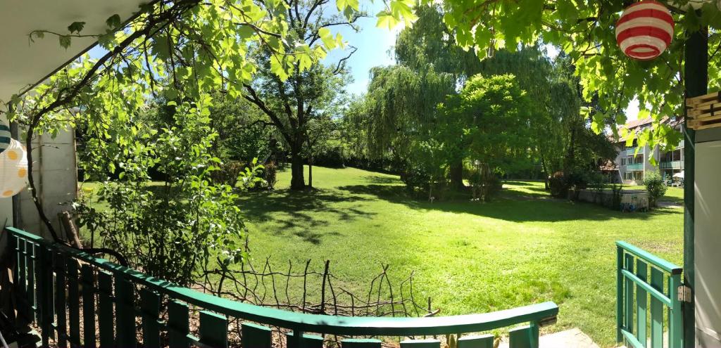 une terrasse couverte avec une clôture verte et une cour arborée dans l'établissement Geneva Bernex - shared appartement roomate homestay - tramway 14 TPG - ViaRhôna, à Genève