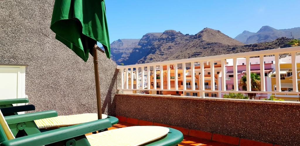 a balcony with chairs and an umbrella and a building at 2 bedrooms appartement with furnished terrace and wifi at Santiago del Teide 1 km away from the beach in Puerto de Santiago