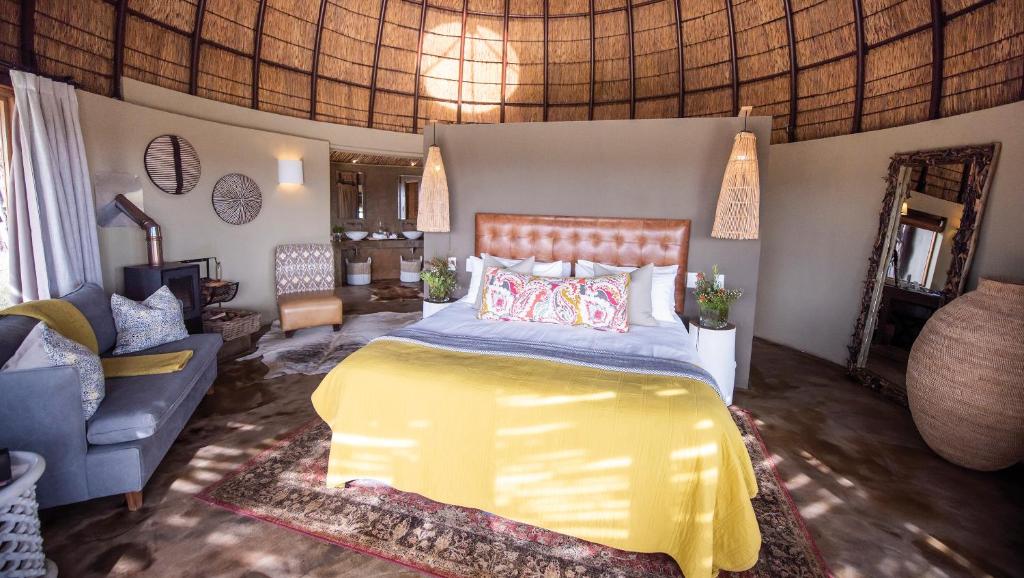 a bedroom with a yellow bed and a couch at Gondwana Game Reserve in Kleinberg