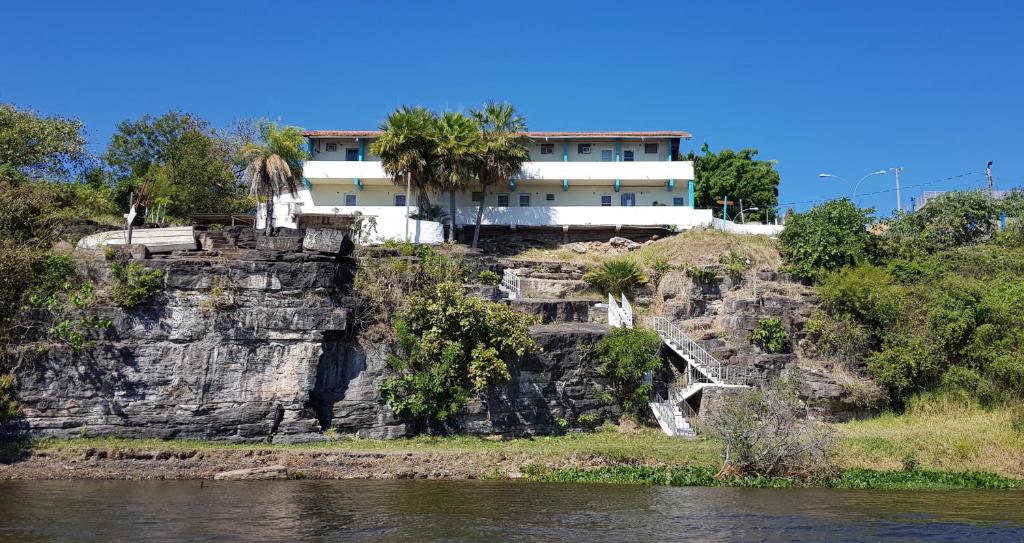 a house on top of a cliff next to the water at Pousada Pantanal in Ladário