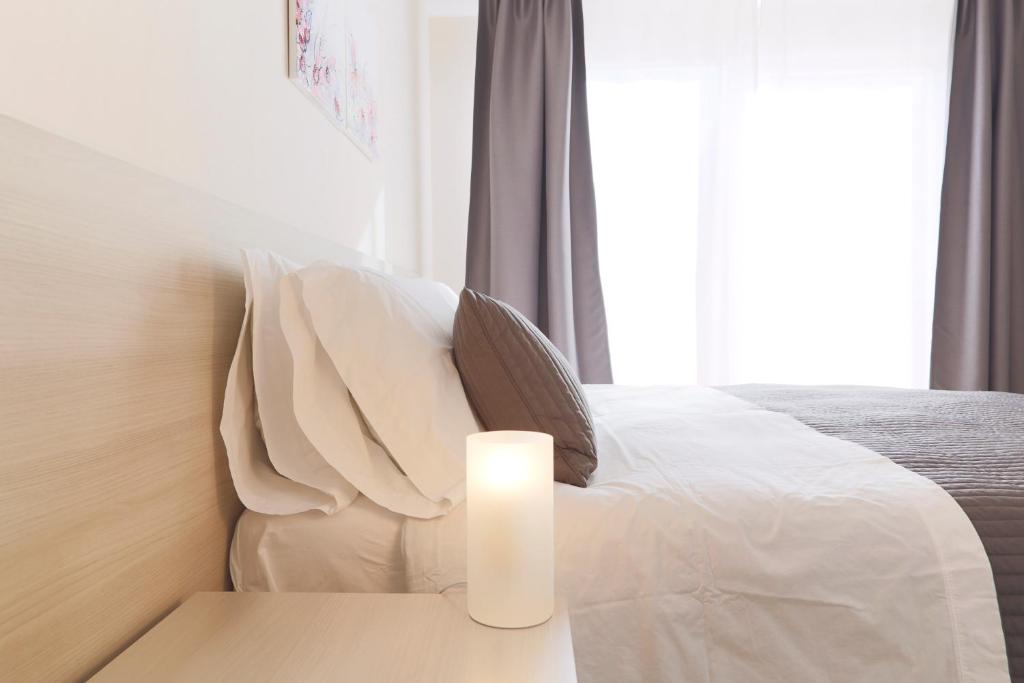 Un dormitorio con una cama blanca con una vela sobre una mesa en Casa Vacanze Bella Giulia en Ragusa