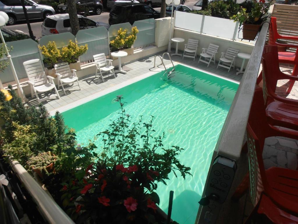 uma vista superior de uma piscina com cadeiras e plantas em Hotel Arno em Rimini