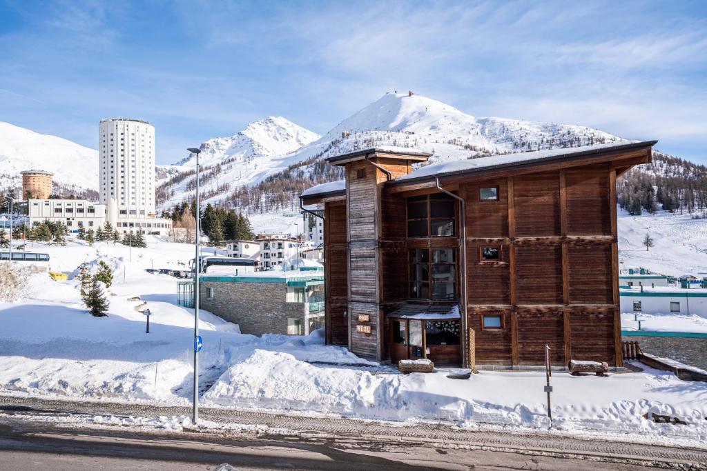 a wooden building in the snow with a mountain at Chalet Weal in Sestriere
