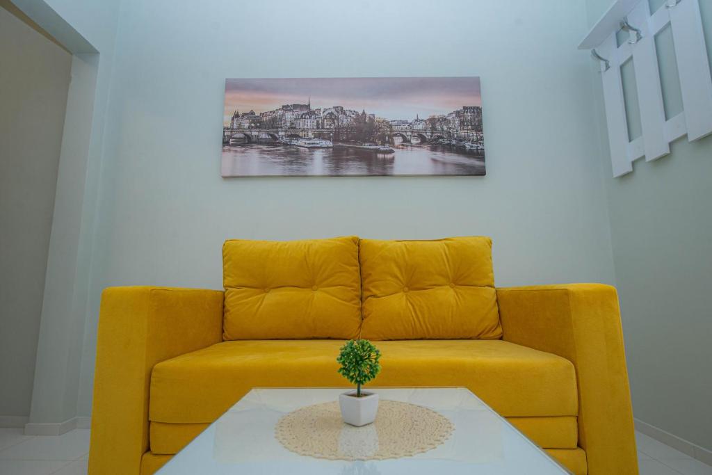 Apartments Biskupović في Muo: أريكة صفراء في غرفة المعيشة مع زرع على طاولة