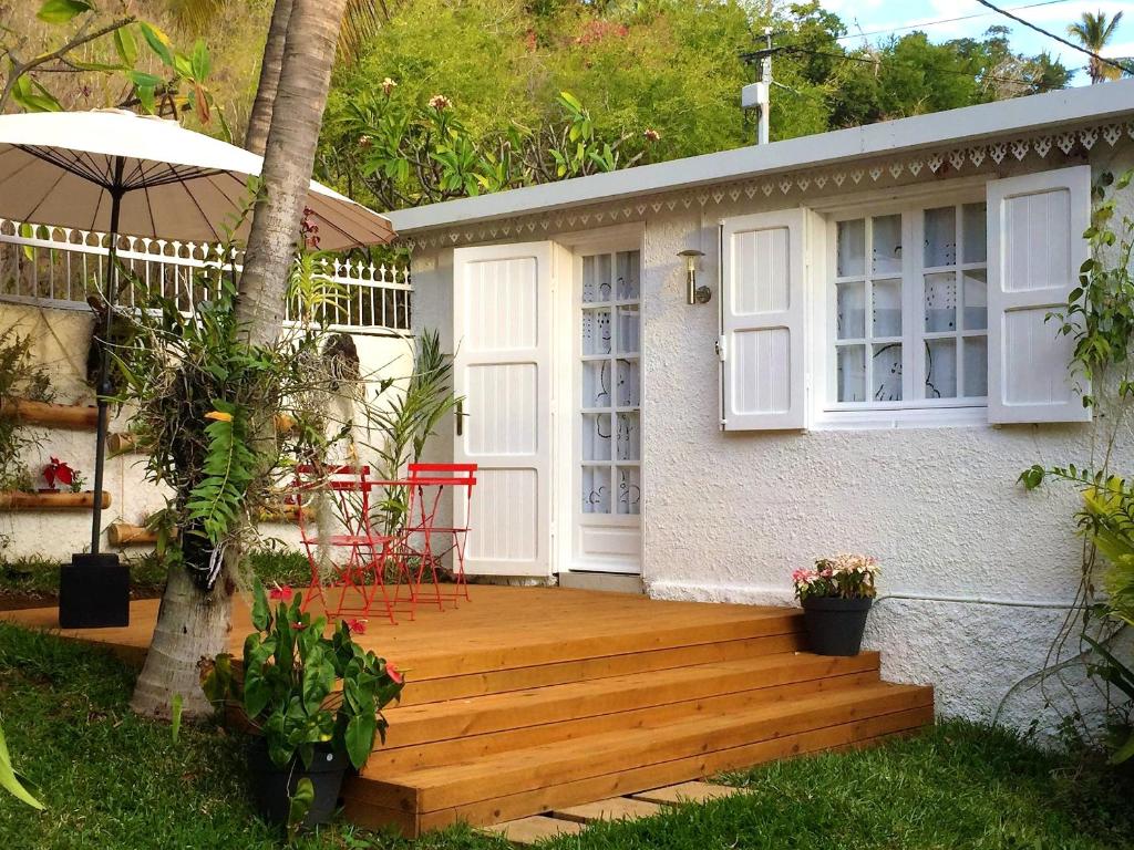 a house with a wooden deck in the yard at Studio at Boucan Canot 900 m away from the beach with enclosed garden and wifi in Boucan Canot