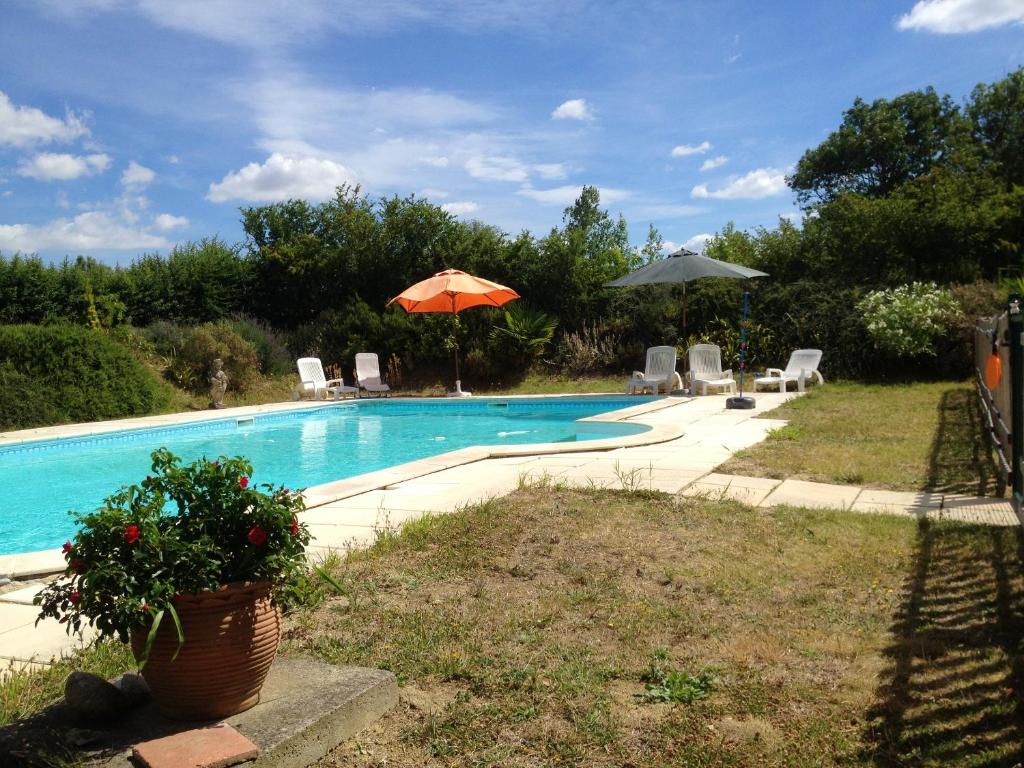 a swimming pool with an orange umbrella and chairs at Manoir enchanteur à Cailhau avec piscine privée sécurisée in Cailhau