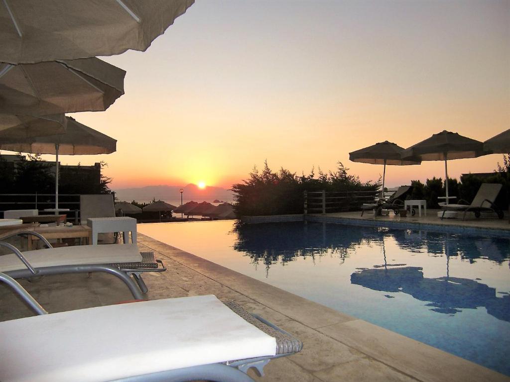 a swimming pool with a sunset in the background at 3 bedrooms villa at TurgutreisBodrum 800 m away from the beach with sea view shared pool and enclosed garden in Karabağ