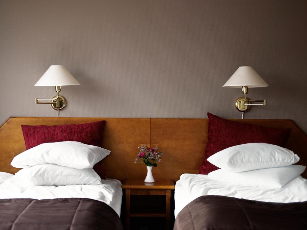 two beds in a hotel room with two lamps at Hotel Terraza in Ljungby
