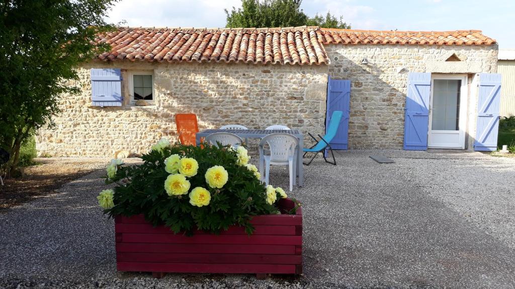 ein Haus mit einem Tisch und Blumen davor in der Unterkunft La maison neuve in Fontaines